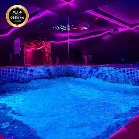 Grupo de personas disfrutando en el club, ambiente vibrante con luces violeta y magenta