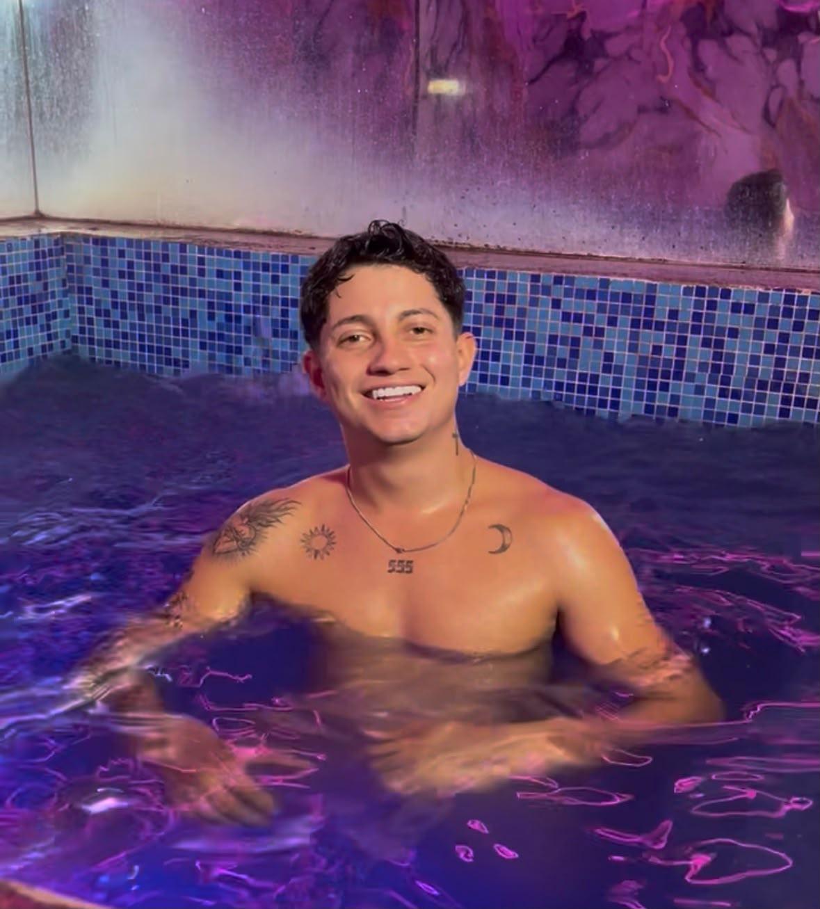 Jacuzzi principal con varios visitantes en traje de baño, iluminación violeta cálida